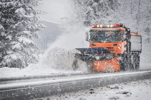 Maintenance highway in winter. Snow plowing. Snow plow truck in snowfall. Truck cleaning snow from road.