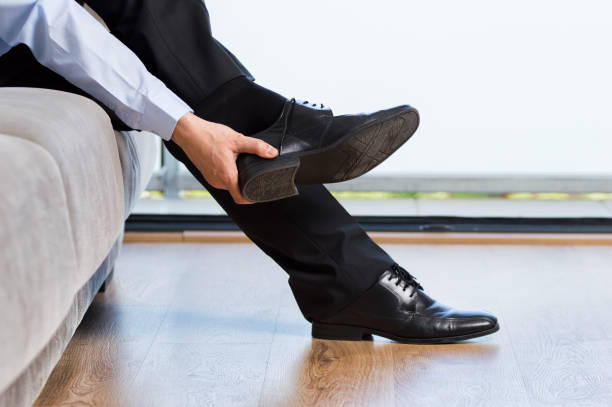 businessman taking off shoes after work at home Profile of a tired businessman taking off shoes after work at home undressing stock pictures, royalty-free photos & images