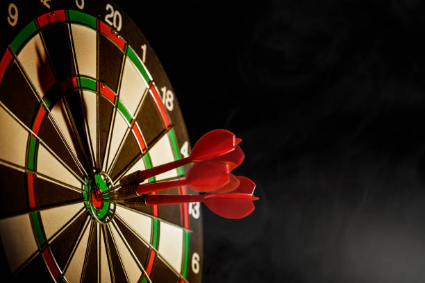 hitting the bulls eye on the black background - target aspirations bulls eye dart imagens e fotografias de stock