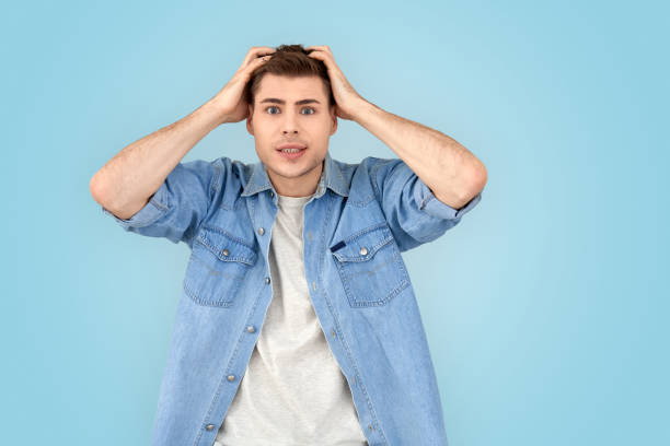 istock Freestyle. Young man in jean jacket standing isolated on gray scratching head thinking of creative idea 1210842925