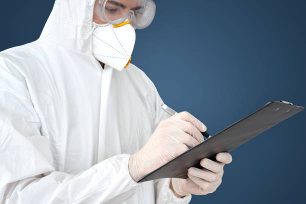 istock Doctor in protective suit and face mask writing on clipboard 1210842936