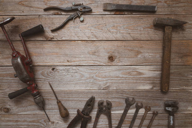 istock Vintage hand tools on a wooden background. Hand drill, hammer, chisel, pliers, puncher and wrenches neatly organized with a space copy opening. Carpentry, diy, craftsmanship concept, top view 1210844871