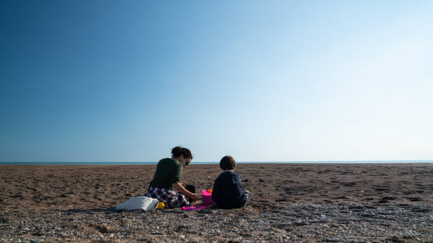 istock Little Boy Playing Together With His Nanny On Beach Sand 1210845713