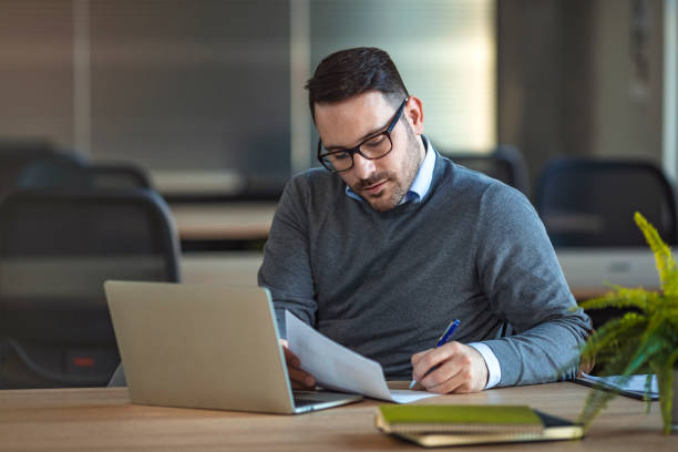 istock Young man sitting in office and working on laptop 1210848148