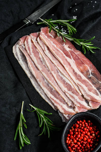 istock Bacon on a stone cutting Board. Pork meat. Black background. Top view 1210851483