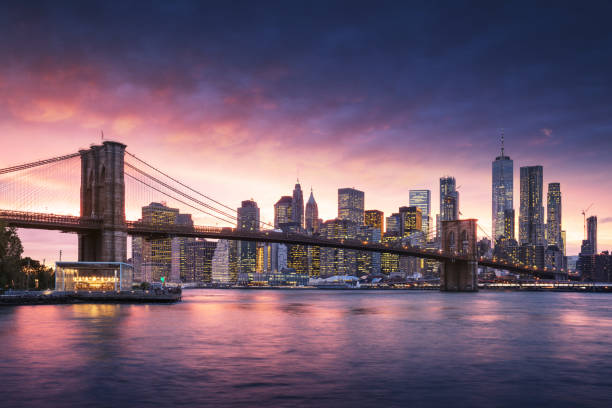 famous brooklyn bridge in new york city with financial district - downtown manhattan in background. sightseeing boat on the east river and beautiful sunset over jane's carousel. - skyline new york city brooklyn bridge new york state imagens e fotografias de stock