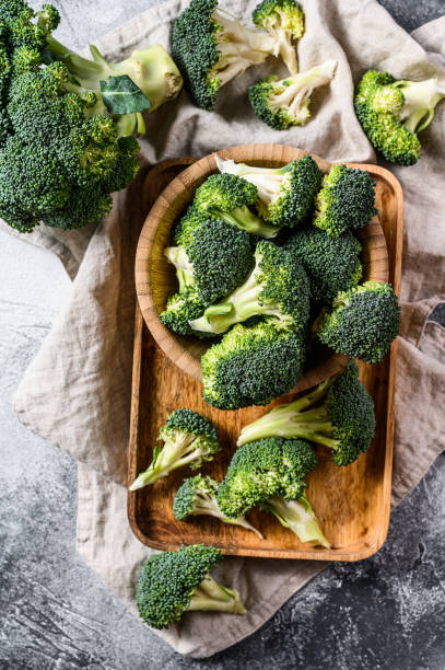 istock Raw broccoli in a wooden bowl. Gray background. Top view 1210854440