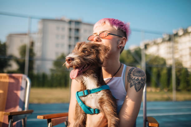 Tattooed woman bonding with her pet Woman relaxing on a sports court with her pet and friends hipster dog stock pictures, royalty-free photos & images