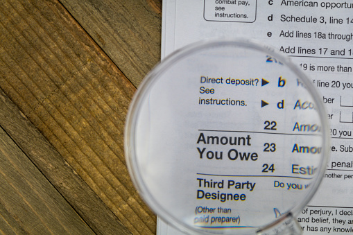 Tax Form filing business concept flat lay wooden board with calculator, glasses, magnifying glass.  Pay taxes file taxes.