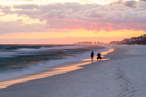 long exposure sunset in santa rosa beach with pensacola coast in florida panhandle at gulf of mexico ocean waves with silhouette of people - florida weather urban scene dramatic sky imagens e fotografias de stock