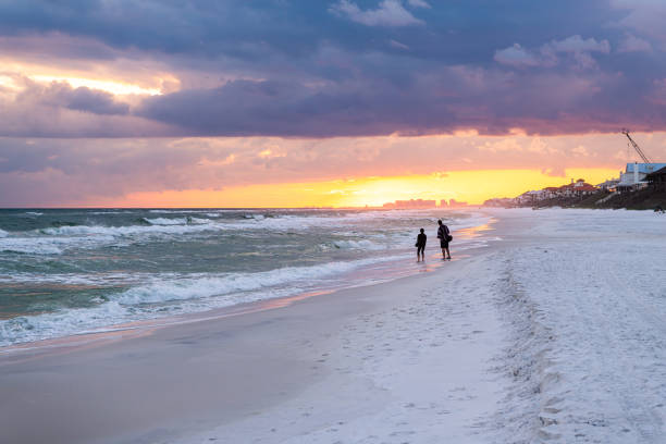 colorful pastel sunset in santa rosa beach with pensacola coast in florida panhandle at gulf of mexico ocean waves with silhouette of people - florida weather urban scene dramatic sky imagens e fotografias de stock