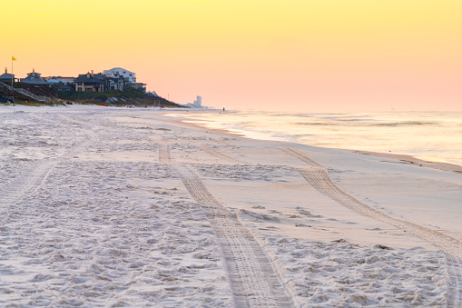 Light yellow orange sunrise in Santa Rosa Beach, Florida with coastline coast holiday homes in panhandle with ocean gulf of mexico waves crashing