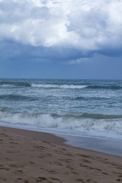 istock Grey storm clouds over sandy beach with dark blue water 1210861653