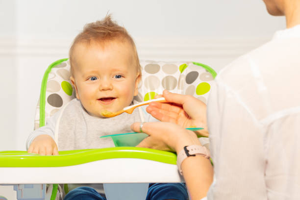 istock Mother feed little toddler baby from plastic spoon 1210862801