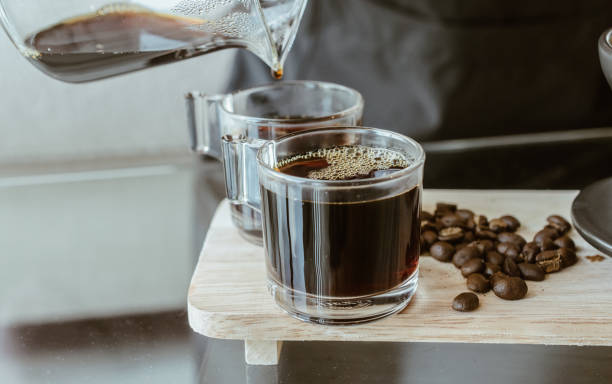 coup de barista versant un café chaud après goutte à goutte dans une tasse de café en verre. - water human hand people women photos et images de collection