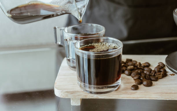 コーヒーのグラスカップに滴り落ちた後、ホットコーヒーを注ぐバリスタのクロップドショット。 - コーヒー栽培 ストックフォトと画像