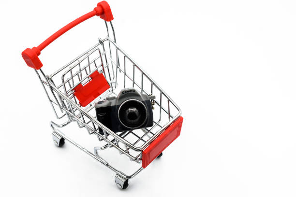 istock A shopping cart carrying toy camera isolated on white background. 1210877493