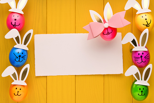 Easter decoration on yellow wooden background with an empty card