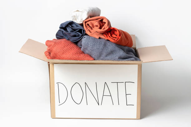 istock Clothes in cardboard box and the inscription Donate on a white background. 1210880123