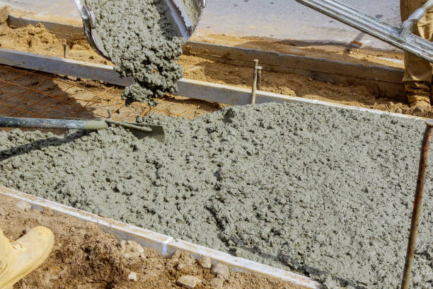 istock Construction worker pour cement for sidewalk in concrete works with mixer truck with wheelbarrow 1210882678