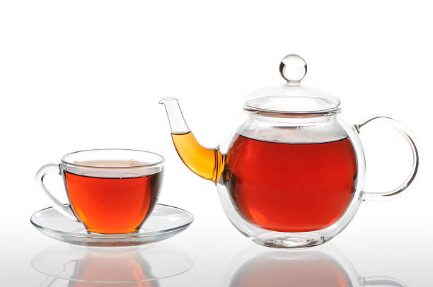 Teapot and cup with black tea on a white background stock photo