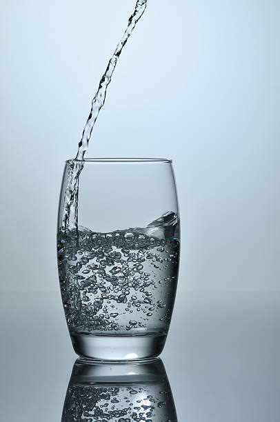 Stream of water falling in whe glass stock photo