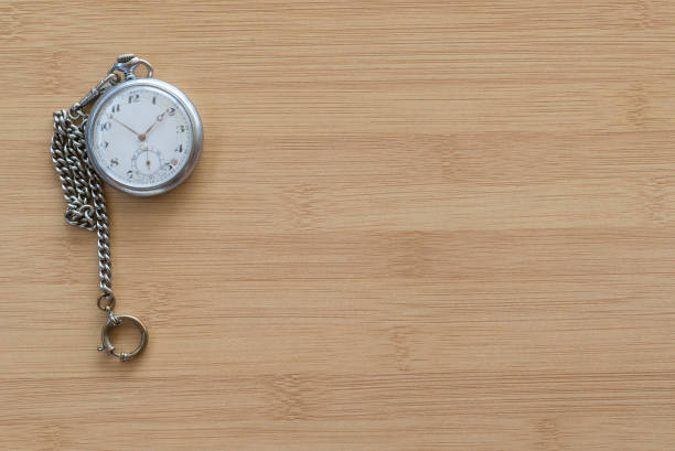 An old pocket watch and chain on a timber surface.