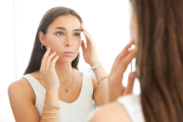 Young Woman Looking her Acne Scars in the Mirror stock photo