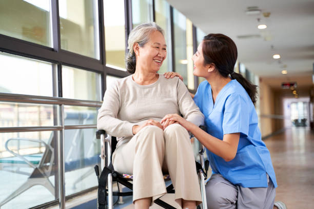 friendly staff of nursing home talking to happy senior woman stock photo