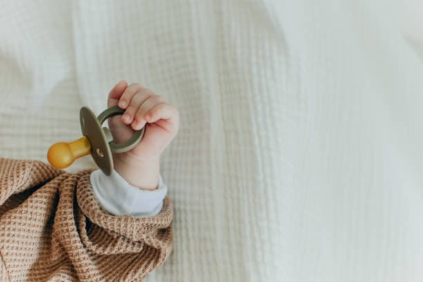 bebê com mamilo. feche acima das mãos do bebê com chupeta. recém-nascido dormindo em um cobertor segurando uma chupeta na mão. - 264 - fotografias e filmes do acervo