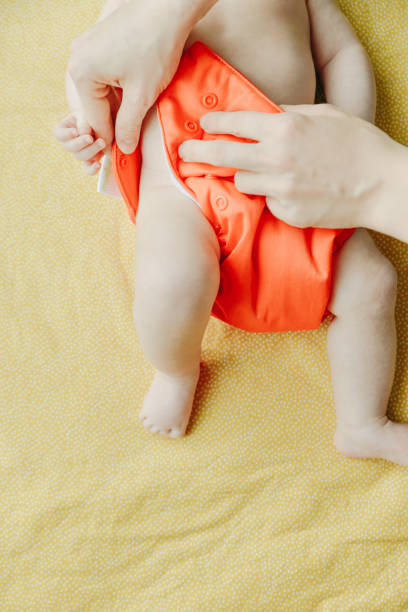 Close up of mother hands put on a baby orange diaper to her newborn. Close up of mother hands put on a baby orange diaper to her newborn oran algeria photos stock pictures, royalty-free photos & images