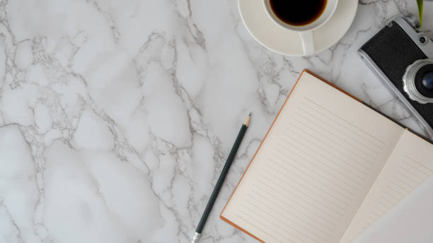 istock Overhead shot of workspace with open notebook, pencil, camera, coffee cup and copy space 1210904715