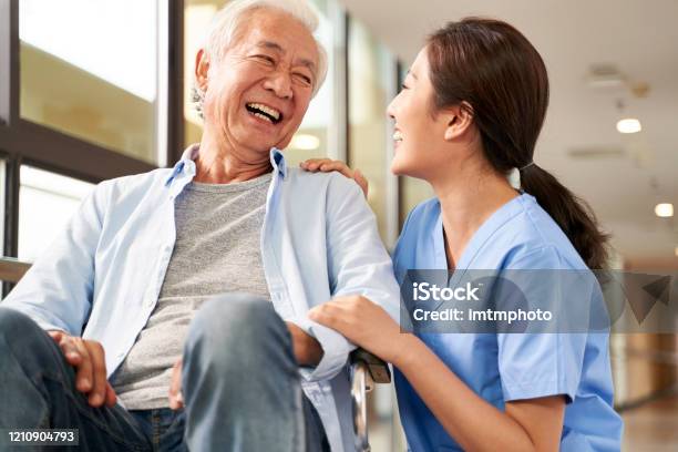 Friendly Asian Caretaker Talking To Senior Patient In Nursing Home Stock Photo - Download Image Now