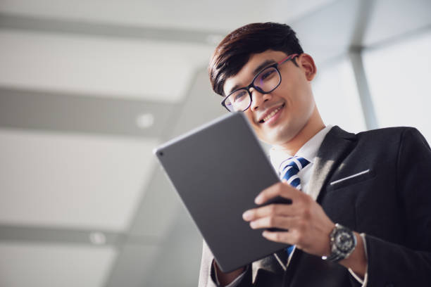 istock A asian handsome young businessman using his tablet and standing on the escalator. Business concept. 1210907688