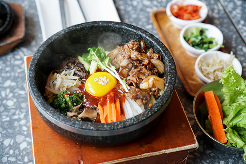 A bowl of rice topped with many vegetable, fried pork and egg yolk, a famous traditional Korean food called \