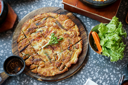 A plate of pizza in Korean style. A crispy and thin pizza dough with vegetable and seafood. (top view)