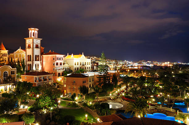 Night illumination of luxury hotel during sunset and Playa de las Américas at background, Tenerife island, Spain