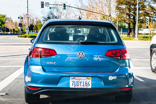 Feb 27, 2020 San Jose / CA / USA - Back view of blue Volkswagen e-Golf driving on a busy city street; VW e-Golf is the electric version of the regular Golf hatchback