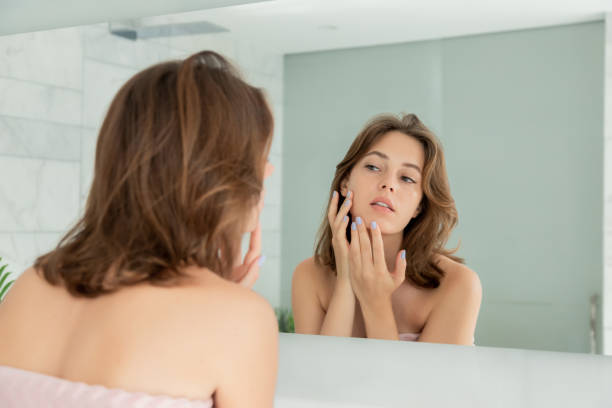 istock Girl looking at mirror examining skin 1210922800