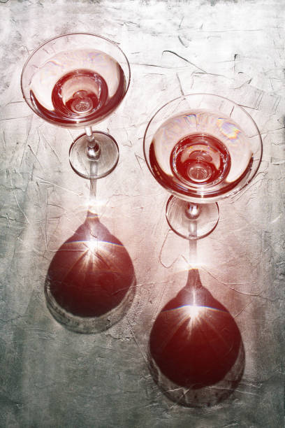 Cocktail glasses and sunlight. Reflection from glass goblets on a silver background with a red tint.