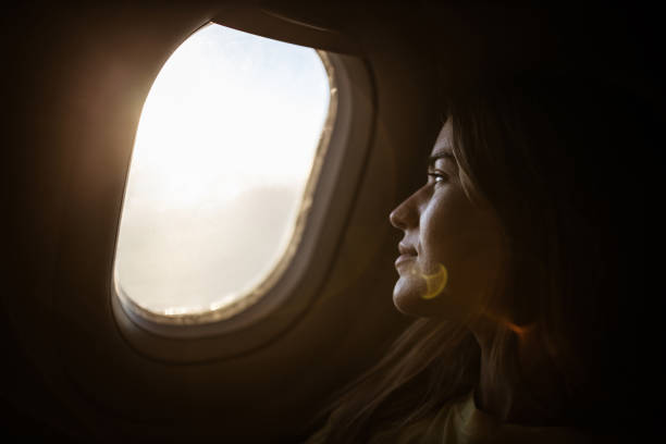 istock Smiling woman enjoying while looking through airplane window. 1210926203