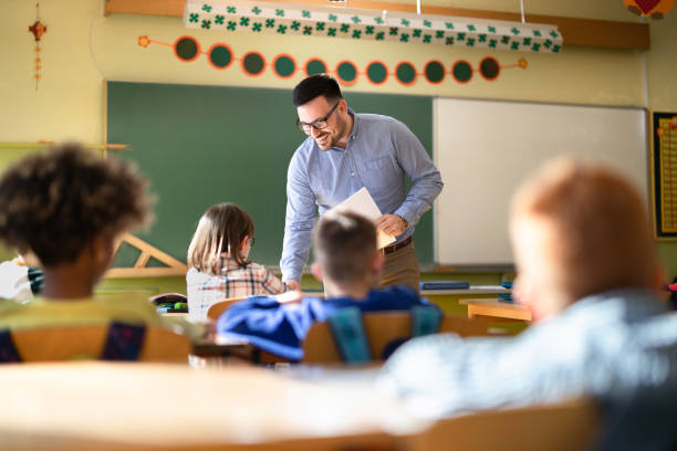 istock Happy male teacher assisting his student on a class at elementary school. 1210928517