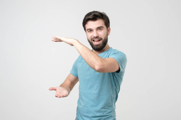 istock Hispanic man with beard holding two hands in front of him and shows the size 1210930607