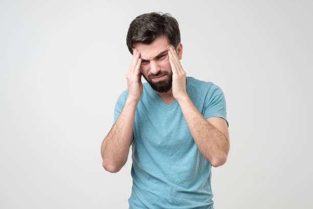 istock Worried young man suffering from headache holding hands on temples. 1210930688