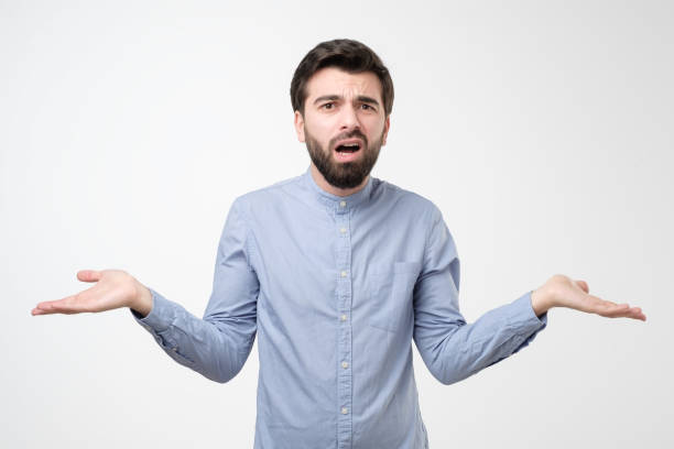istock Guy feeling confused spreading palms and shrugging with awkward expression 1210932437