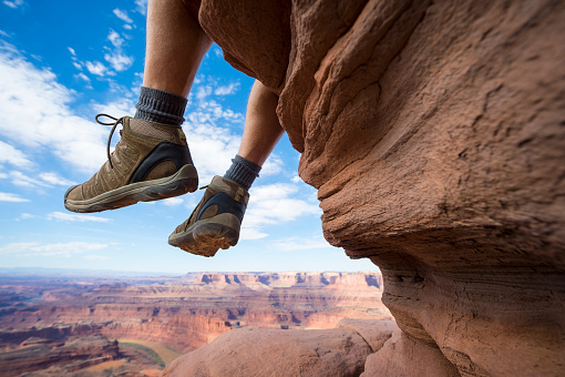 Portrait of the boots of a hiker hanging outdoors above dramatic canyon landscape