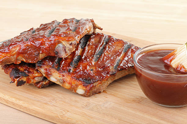Barbecue Spareribs Grilled barbecue spareribs and barbecue sauce on a cutting board barbeque sauce photos stock pictures, royalty-free photos & images