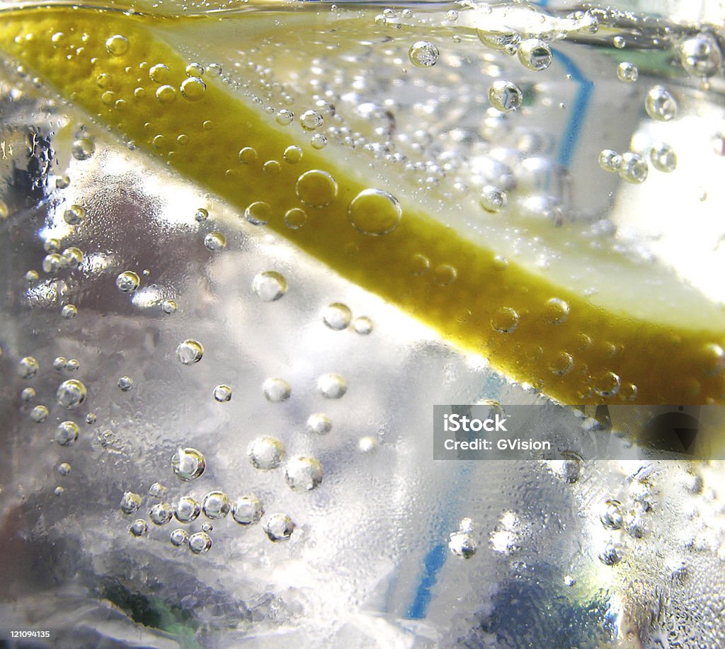 Macro view of fresh lemon infused water with straw close-up of lemon in liquid with bubbles and straw Backgrounds Stock Photo