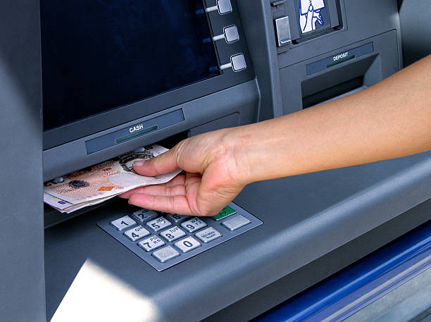 Hand inserting money into an ATM machine stock photo