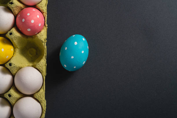 istock Colorful polka dot Easter eggs in egg tray on dark grey black plain background, greeting card, copy space, top view 1210944913